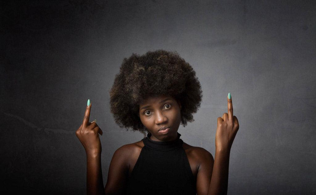 A woman with an afro raises both middle fingers toward the camera.