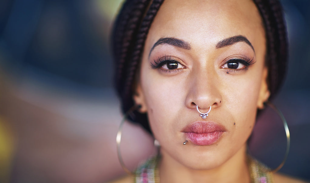 Living with an invisible illness: a portrait of a person with a nose ring and big hoop earrings. 
