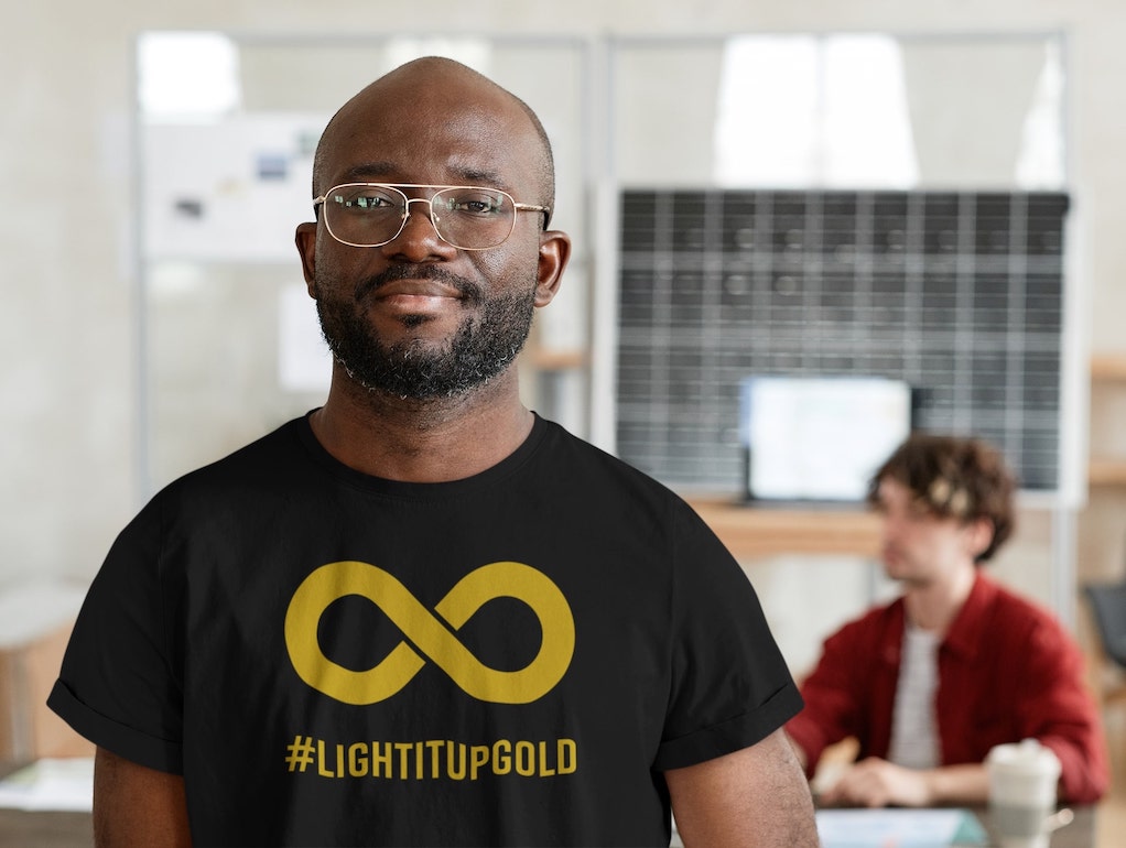 A person wearing a black T-shirt with a gold infinity symbol.