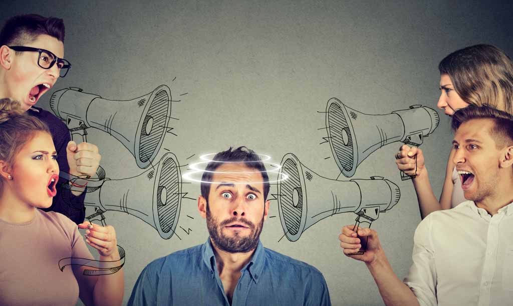 Power of labels in disability identity: an illustration of a group of people screaming in megaphones at a seated person who is clearly scared. Illustration is for an article on the power of labels in disability identity.