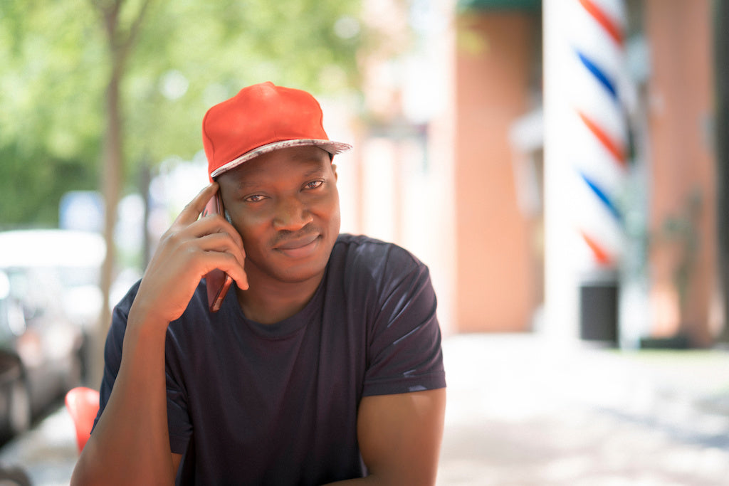 The pros and cons of mental health labels: a man is sitting down outside holding his mobile phone in his hand.