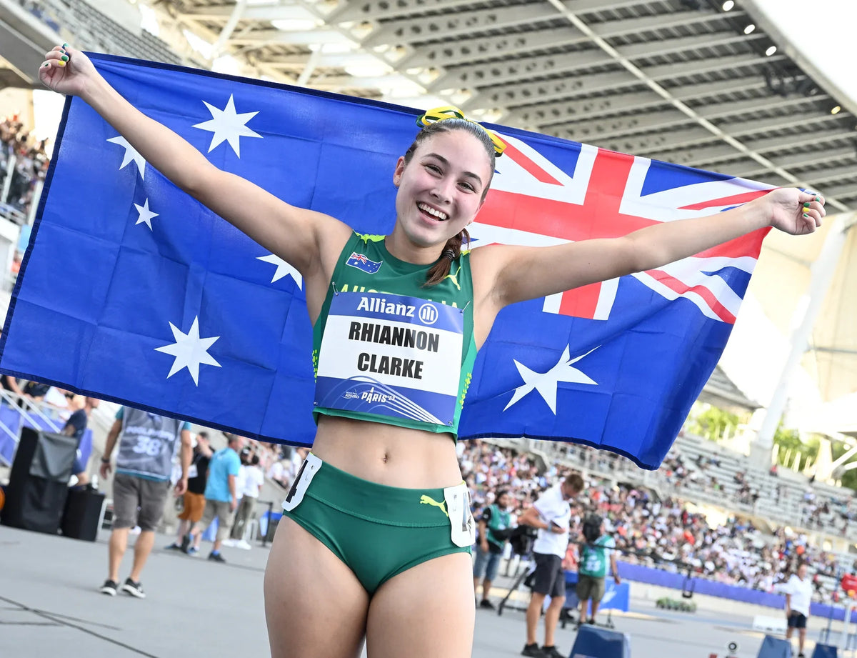 Rhiannon Clarke holds an Australian flag behind her with both arms outstretched at Paris 2023.