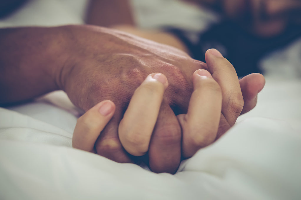 Sexual intimacy with fibromyalgia: a close up photo of a two hands intertwined conveying closeness and intimacy.