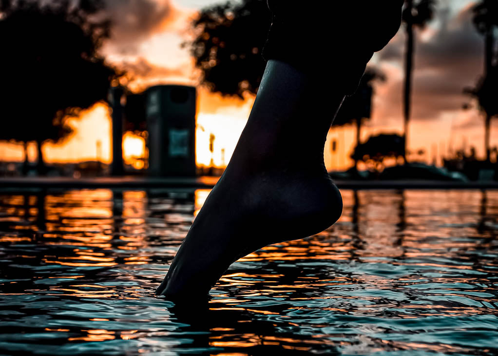 Spina bifida poems: a single foot touches the surface of a lake at dawn as the sunrises behind. 