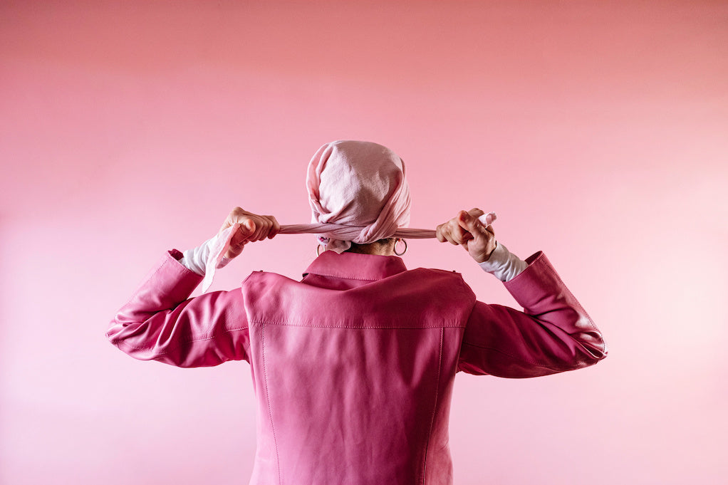 What to do when your mom is diagnosed with breast cancer?  Woman from behind tying a pink scarf on her head, cancer patient.