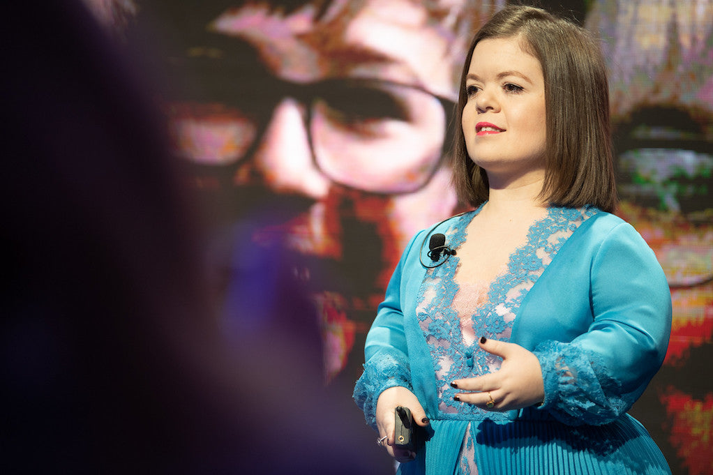 Sinéad Burke, Why design should include everyone, stands on a WEF stage giving a talk.