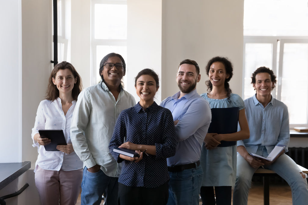 How to create a workplace that supports neurodiversity: six diverse happy employees pose in a group photo.