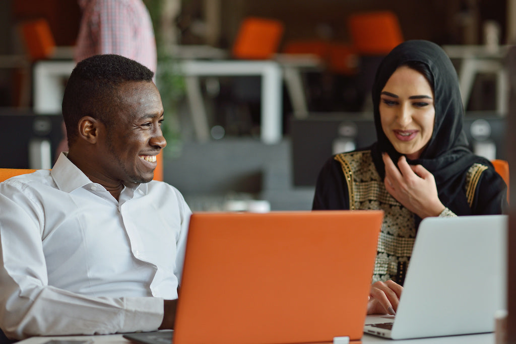 Two colleagues talk across a desk in an office.