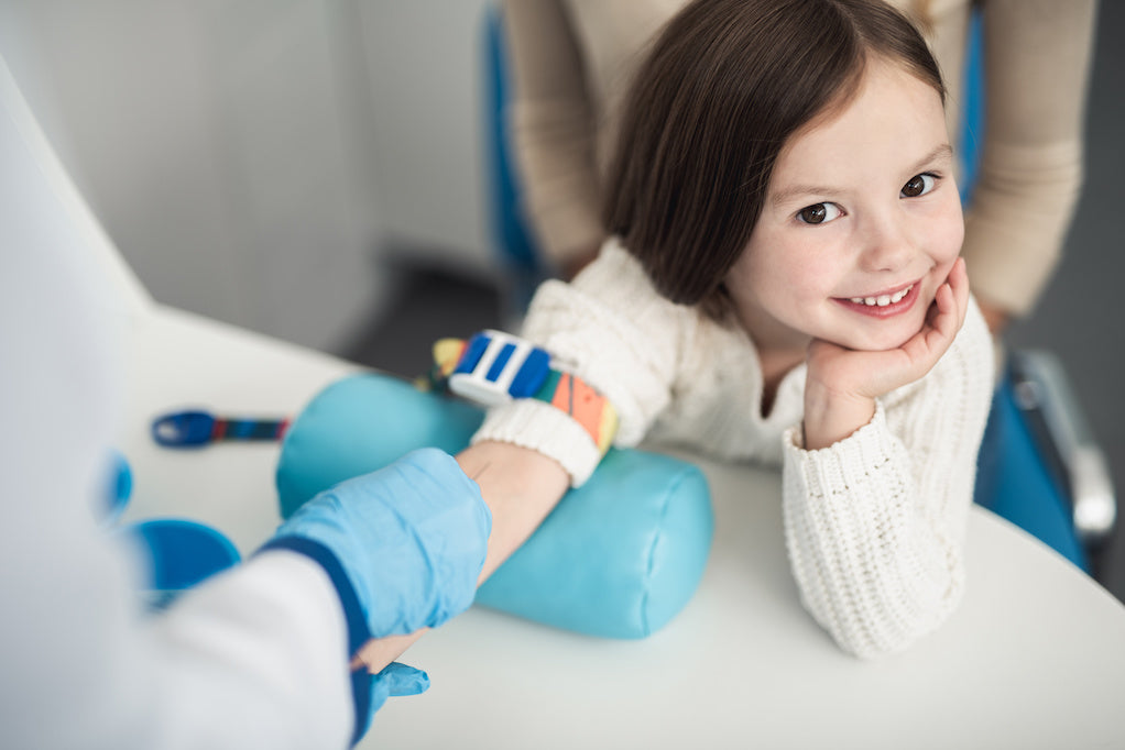 A color photo of a smiling young cancer patient blood draw