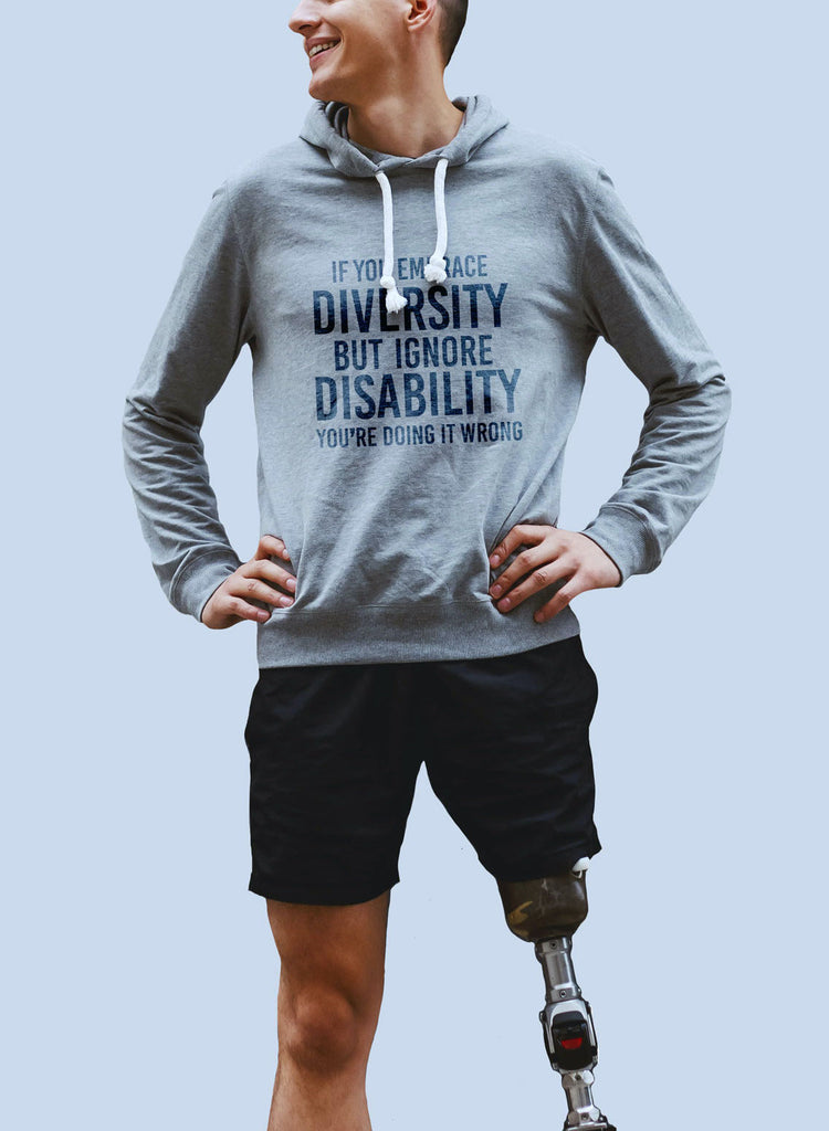 A man with a prosthetic limb is wearing a sweater with the phrase "If you embrace diversity, but ignore disability, you're doing it wrong."