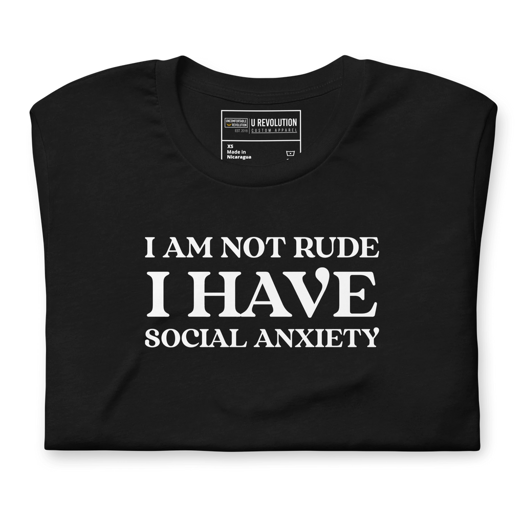 Folded black t-shirt with white text that reads "I Am Not Rude, I Have Social Anxiety." A statement tee for social anxiety awareness