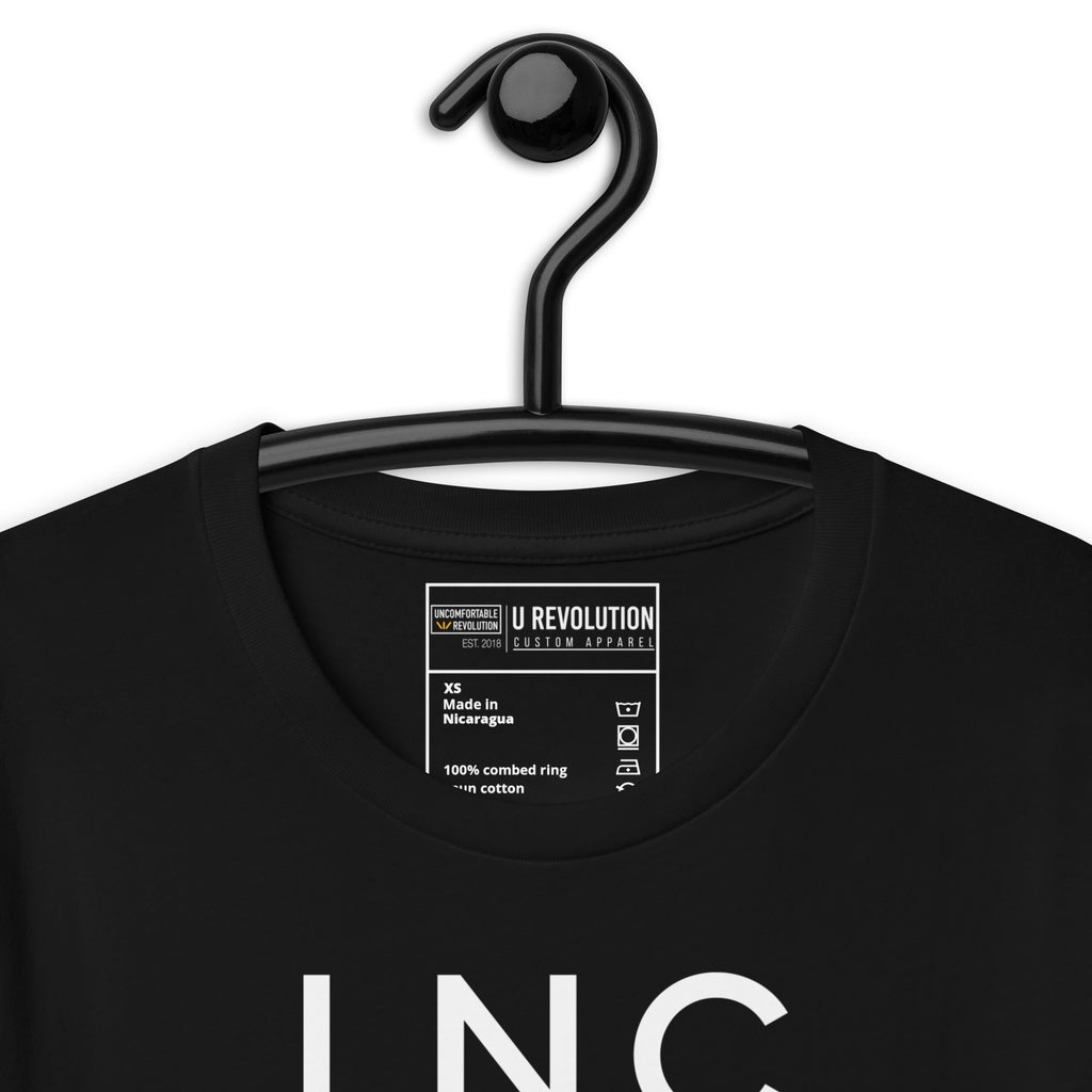 Close-up of the black INCLUSIVE Statement Tee typography – bold and minimalist lettering arranged in three-line format, representing diversity and inclusion.