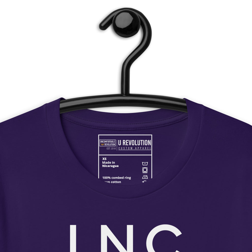Close-up of the purple INCLUSIVE Statement Tee typography – bold and minimalist lettering arranged in three-line format, representing diversity and inclusion.