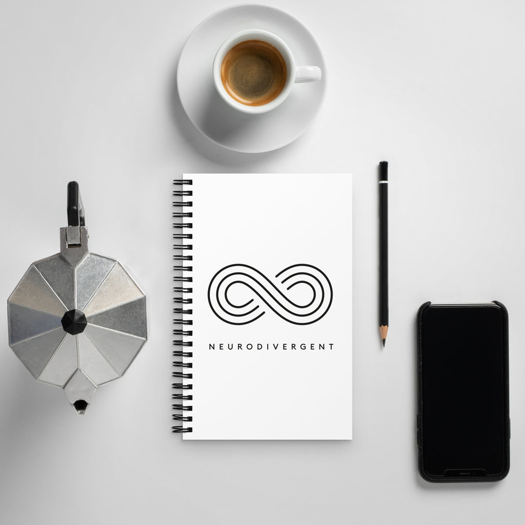 The Infinity Symbol Journal with 'Neurodivergent' text – a notebook celebrating neurodiversity - is displayed n a coffee table.