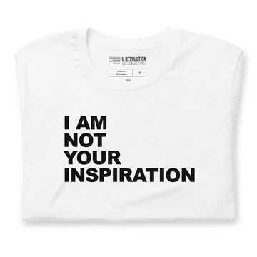 This is a white 'I Am Not Your Inspiration" t-shirt. On the top third of the inspiration shirt is the phrase, "I am not your inspiration," printed over four lines in black upper case letters. The tee is neatly folded.