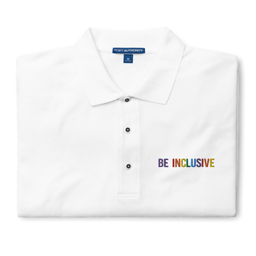 This is a photo of a premium white Rainbow Polo Shirt. On the polo's top right panel is the phrase, Be Inclusive, embroidered in red, orange, yellow, green, indigo, and violet. The word 'be' is only in violet. The polo is folded neatly.