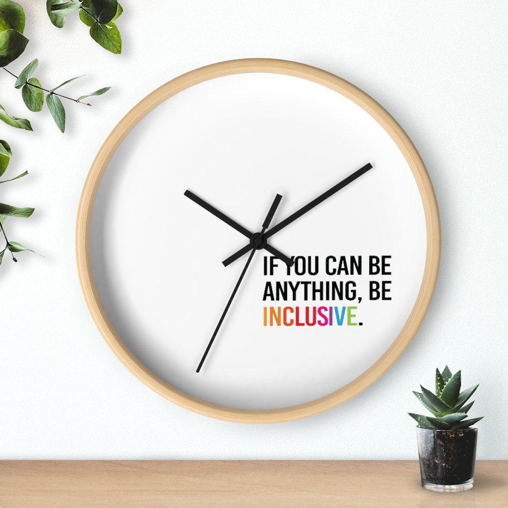 Photo of the clock against a wall with two plants on either side: one hanging from the top left corner and the other in a small pot on a desk.