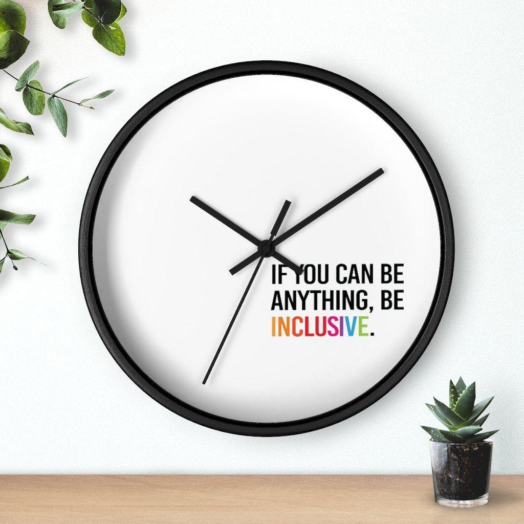 Photo of the clock against a wall with two plants on either side: one hanging from the top left corner and the other in a small pot on a desk.