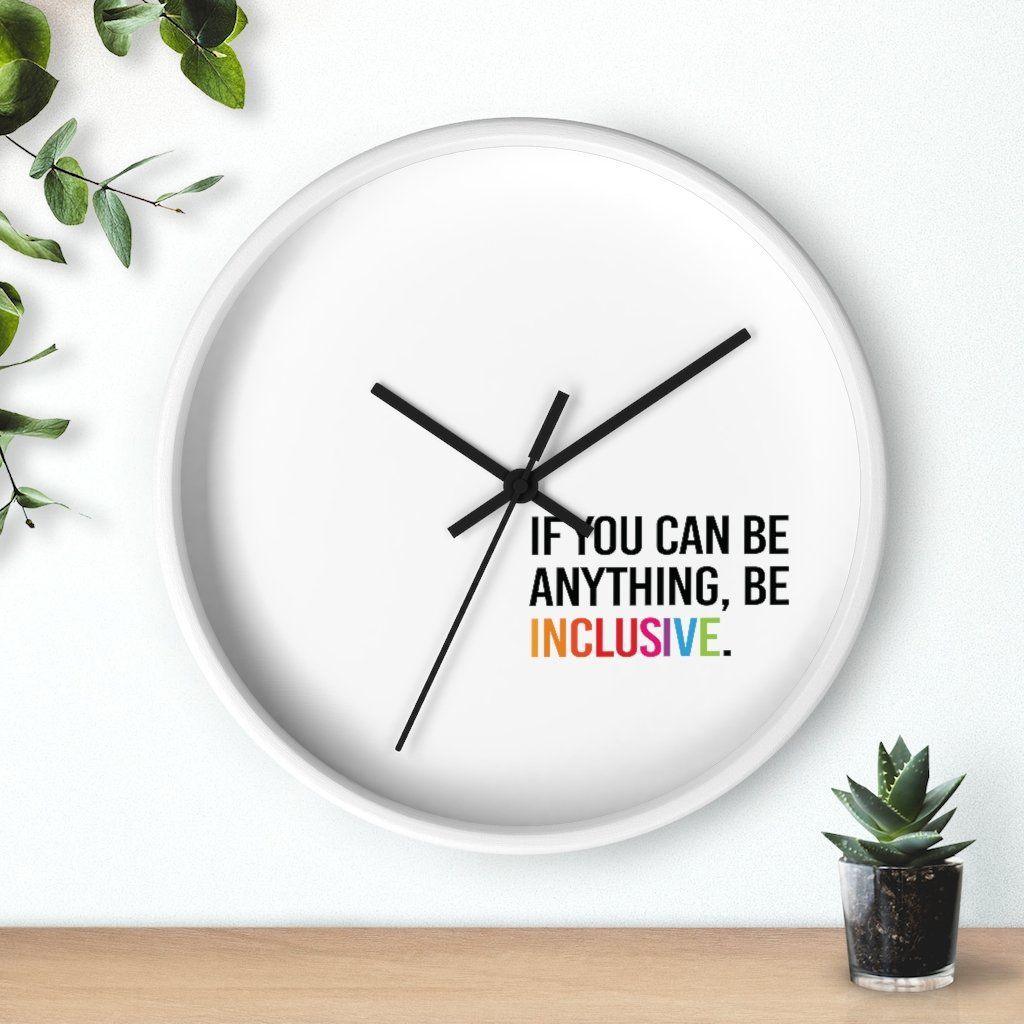 Photo of the clock against a wall with two plants on either side: one hanging from the top left corner and the other in a small pot on a desk.