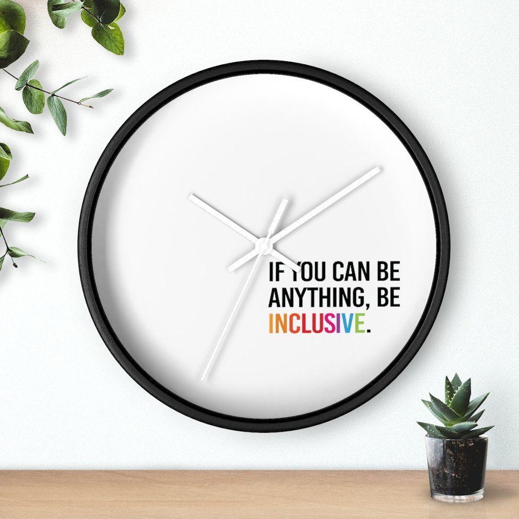 Photo of the clock against a wall with two plants on either side: one hanging from the top left corner and the other in a small pot on a desk.