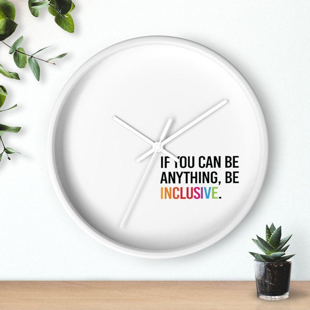 Photo of the clock against a wall with two plants on either side: one hanging from the top left corner and the other in a small pot on a desk.