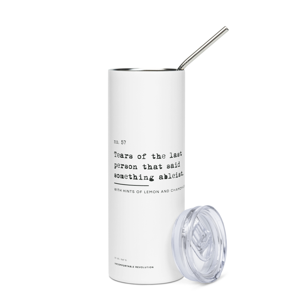 The Ableist Tears Stainless Steel Travel Mug is white, with black text that reads: "no. 57. Tears of the last person that said something ableist. With hints of lemon and chamomile." At the base of the mug is the text: 20oz / 567 gr Uncomfortable Revolution. The mug has a plastic lid and metal straw. The lid is off the mug.