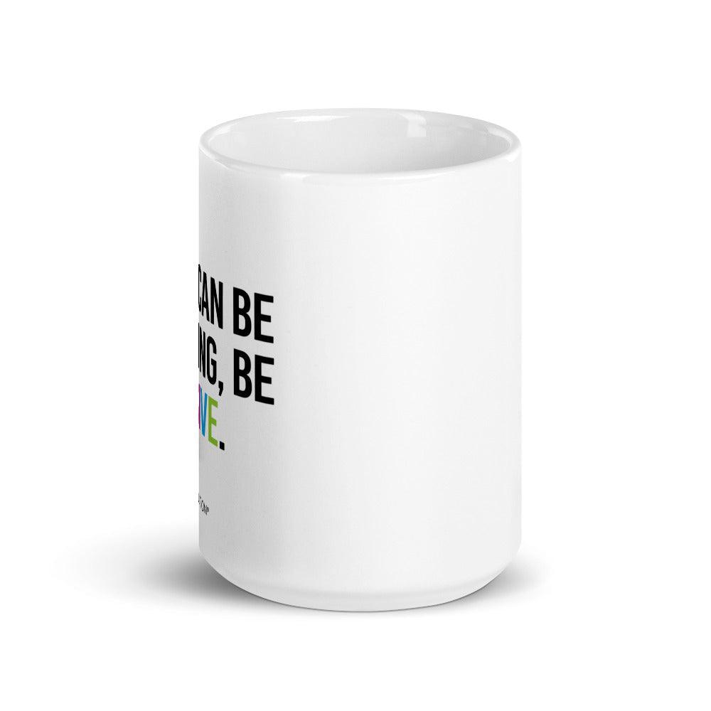 15oz Be Inclusive mug. On the right-hand side of the mug, facing the screen, is the phrase, 'If you can be anything, be inclusive,' printed in large black upper case letters. The word 'inclusive' is in the color of the rainbow. At the bottom edge of the inclusive mug is the word, URevolution, printed in small black upper case letters.