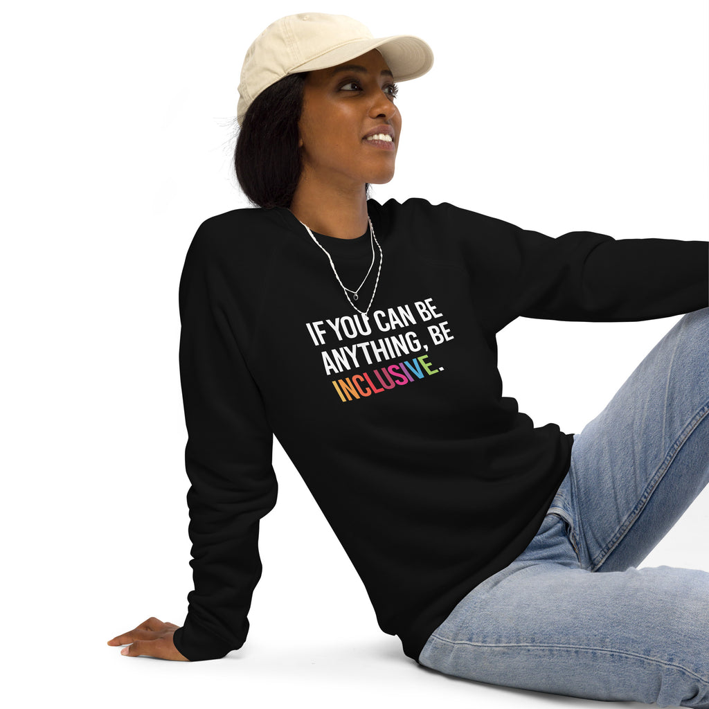 A black Be Inclusive organic sweatshirt. On the front of the organic sweatshirt is the phrase: "If you can be anything, be inclusive," in black upper case letters. All the text is in white, except "Inclusive," which is in rainbow colors. A black female model in a white cap is wearing the sweatshirt.