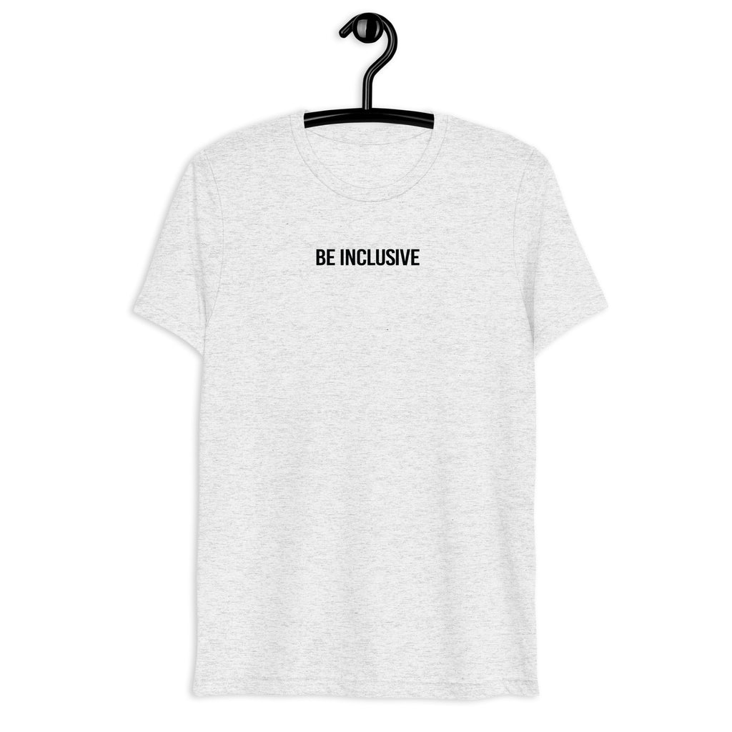 White-fleck unisex tri-blend Be Inclusive t-shirt. Printed in the middle top one-third of the t-shirt in black upper case letters, about one inch high is the phrase - Be Inclusive. The t-shirt is hanging on a black plastic hanger against a blank wall.