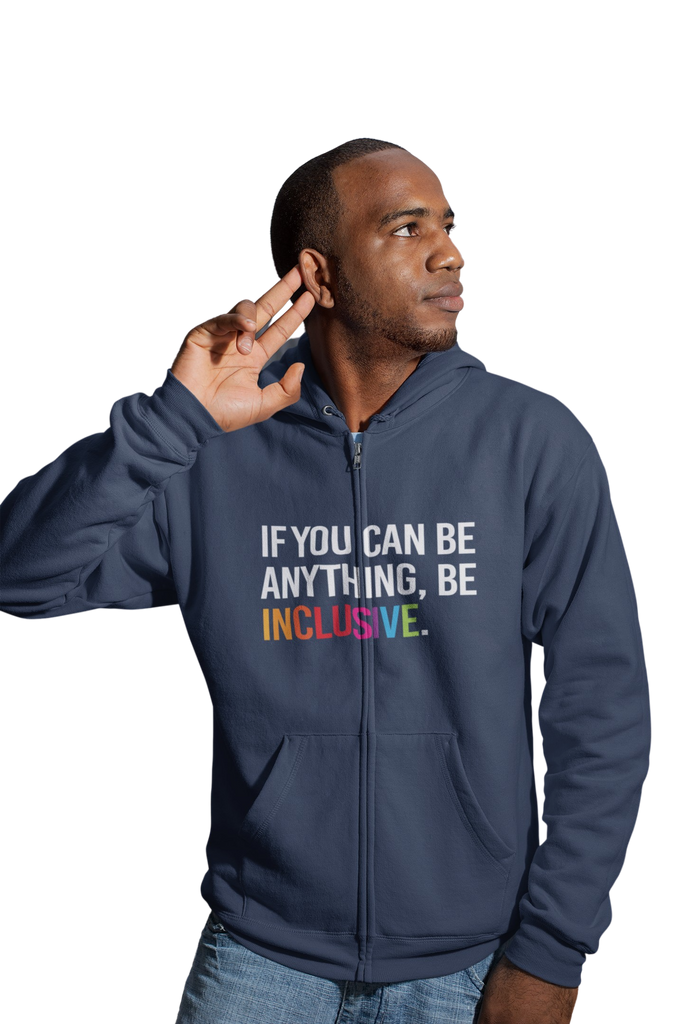 A man is wearing a navy be inclusive zip hoodie. In the middle center of the hoodie, between the top of the pockets and collar, is the phrase, 'If you can be anything, be inclusive,' printed in white upper case letters. The word 'inclusive' is printed in rainbow-like colors.