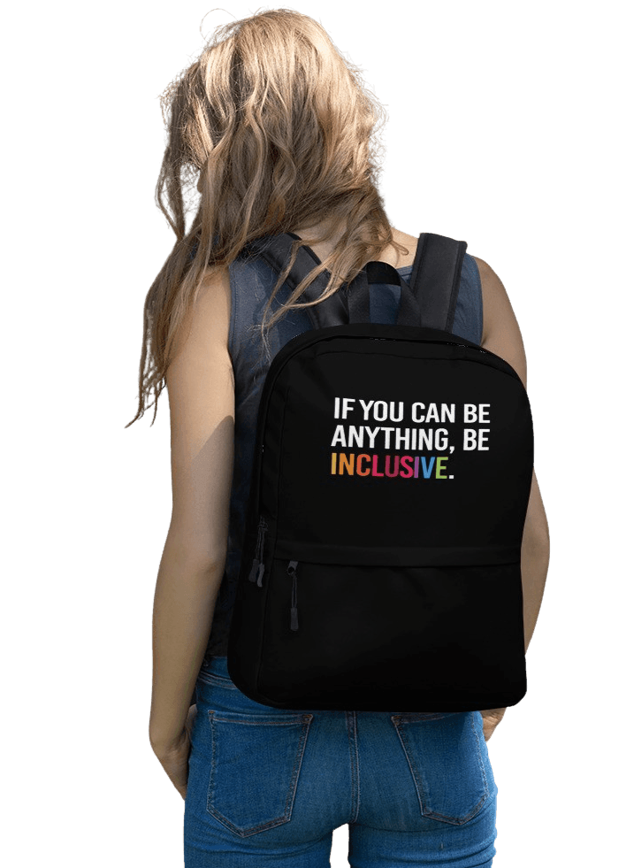 This is a photo of URevolution's black Be Inclusive backpack. In the top of half of the backpack, the phrase, 'If you can be anything, be inclusive,' is printed in white upper case letters. The rest of the backpack is black. The word 'inclusive' is in the color of the rainbow.  The backpack is being worn on the back of model with long fawn hair, wearing a navy tank top and blue jeans.