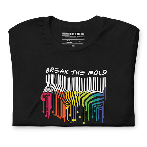 This is a photo of a Break the Mold t-shirt. In the middle of the t-shirt is a graphic of zebra in the silhouette of a barcode. The top half of the zebra are vertical white stripes, which then change just below the back into the colors of the rainbow. The bottom of each stripe has a paint drip mark. Just above the zebra's back is the phrase, in upper case, 'break the mold.' 