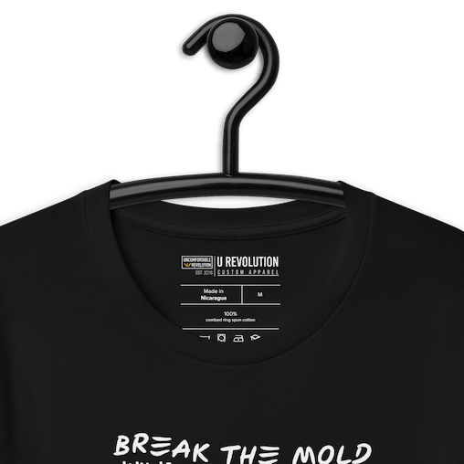 This is a photo of a Break the Mold t-shirt. In the middle of the t-shirt is a graphic of zebra in the silhouette of a barcode. The top half of the zebra are vertical white stripes, which then change just below the back into the colors of the rainbow. The bottom of each stripe has a paint drip mark. Just above the zebra's back is the phrase, in upper case, 'break the mold.' 