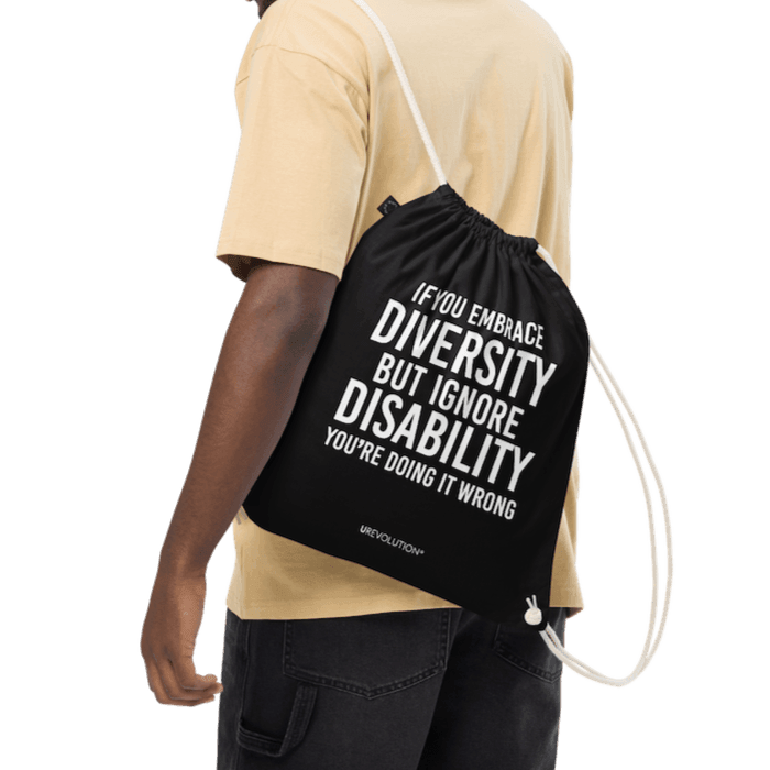 A black Embrace Diversity organic cotton drawstring bag. The middle of the drawstring bag features the phrase, printed in large white upper case letters, "If you embrace diversity but ignore disability, you're doing it wrong." The phrase fills 80% of the bag. 