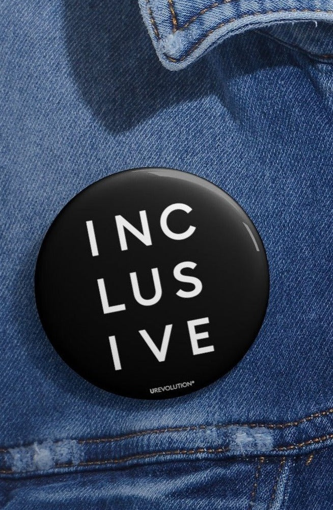A person wearing the INCLUSIVE Statement Pin on a backpack, showcasing its bold design for social justice advocacy.