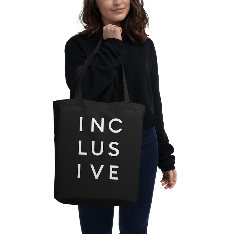 Person carrying the INCLUSIVE Statement Tote, a sustainability-conscious organic cotton bag for everyday use.