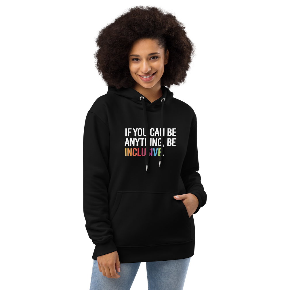 Photo of a black premium eco-friendly be inclusive hoodie. In the top one-third of the hoodies is the phrase, 'If you can be anything, be inclusive.' printed on it in white upper case letter. The word 'inclusive' is printed in rainbow-like colors.  The hoodie is worm by a female model.