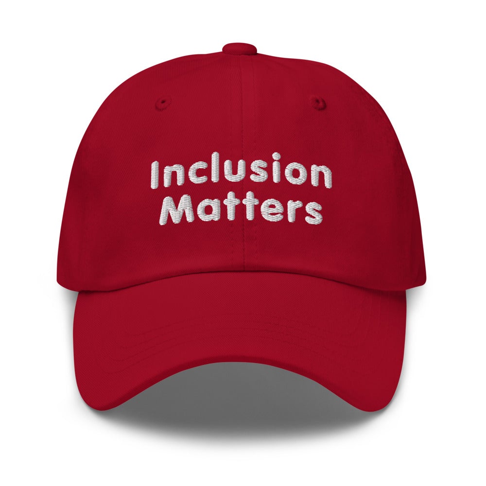 This is a photo of a cranberry-colored Inclusion Matters Baseball Cap. On the front of the baseball cap above the visor are two words, 'Inclusion Matters.' printed in white sentence case letters over two lines.