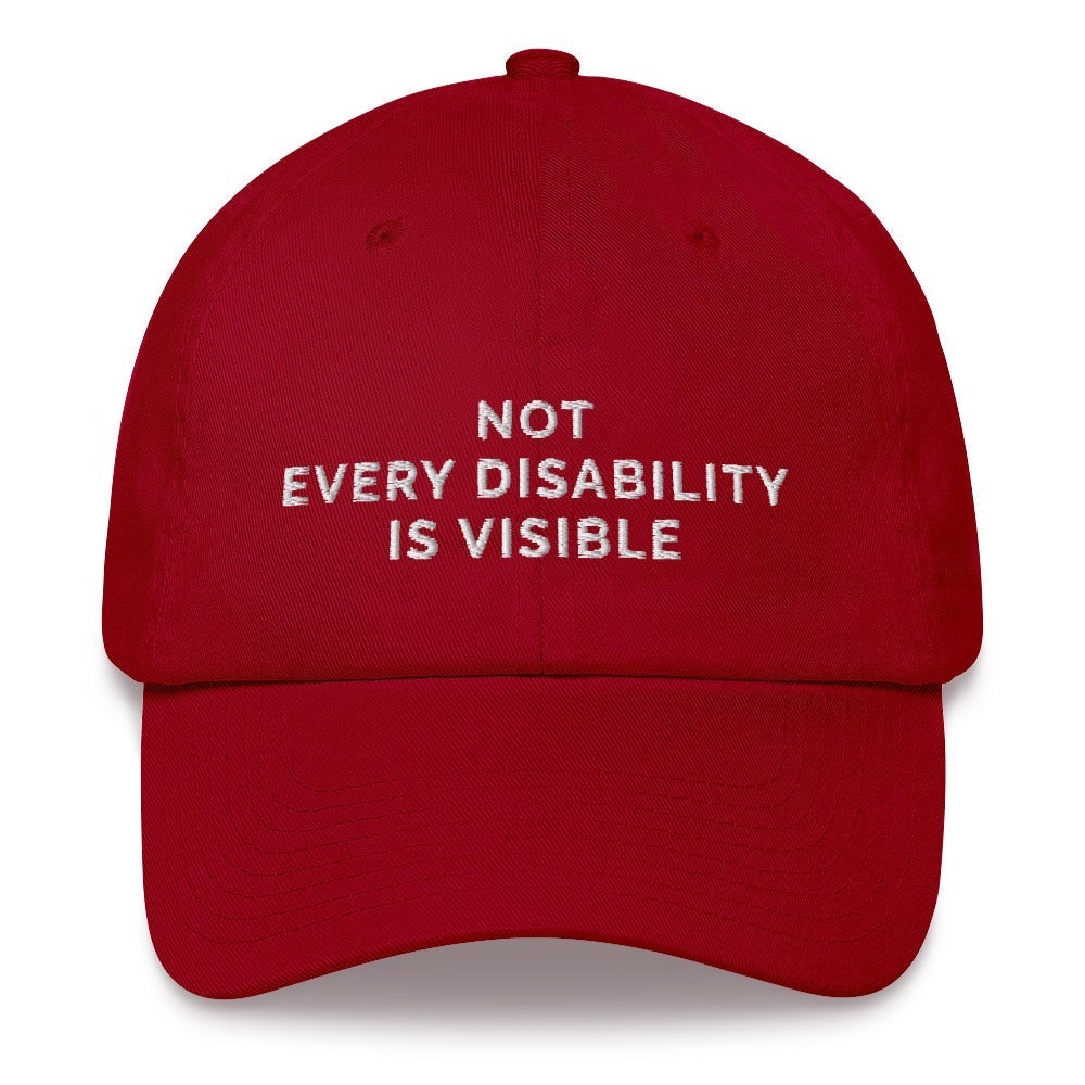 This is a photo of a cranberry 'not every disability is visible' cap. Embroidered, on the front of the cap in white upper case letters, is the phrase 'Not Every Disability Is Visible.'