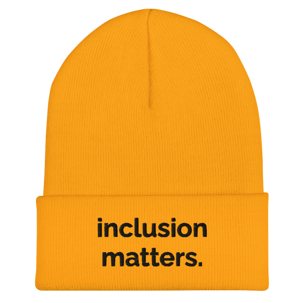 A gold Inclusion Matters beanie against a plain white background. On the front of the beanie the phrase, 'Inclusion Matters,' is embroidered on it in black sentence case letters over two lines.
