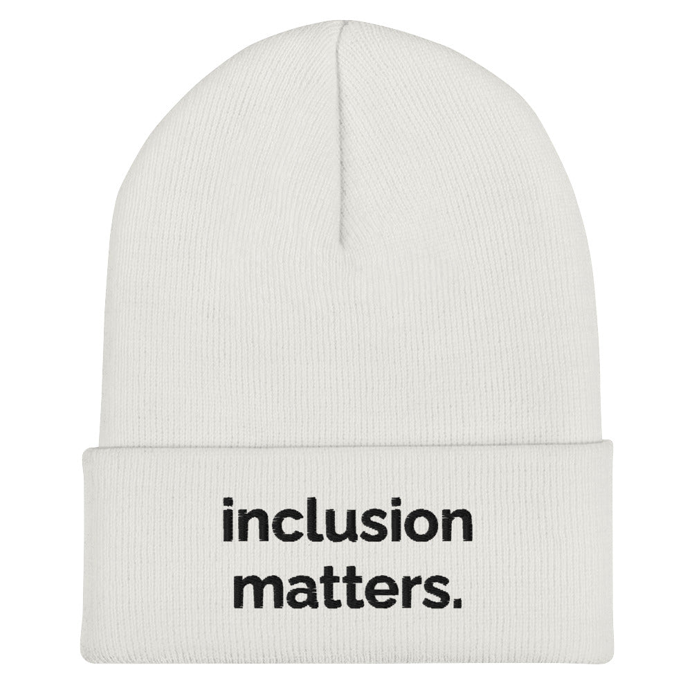 A white Inclusion Matters beanie against a plain white background. On the front of the beanie the phrase, 'Inclusion Matters,' is embroidered on it in black sentence case letters over two lines.
