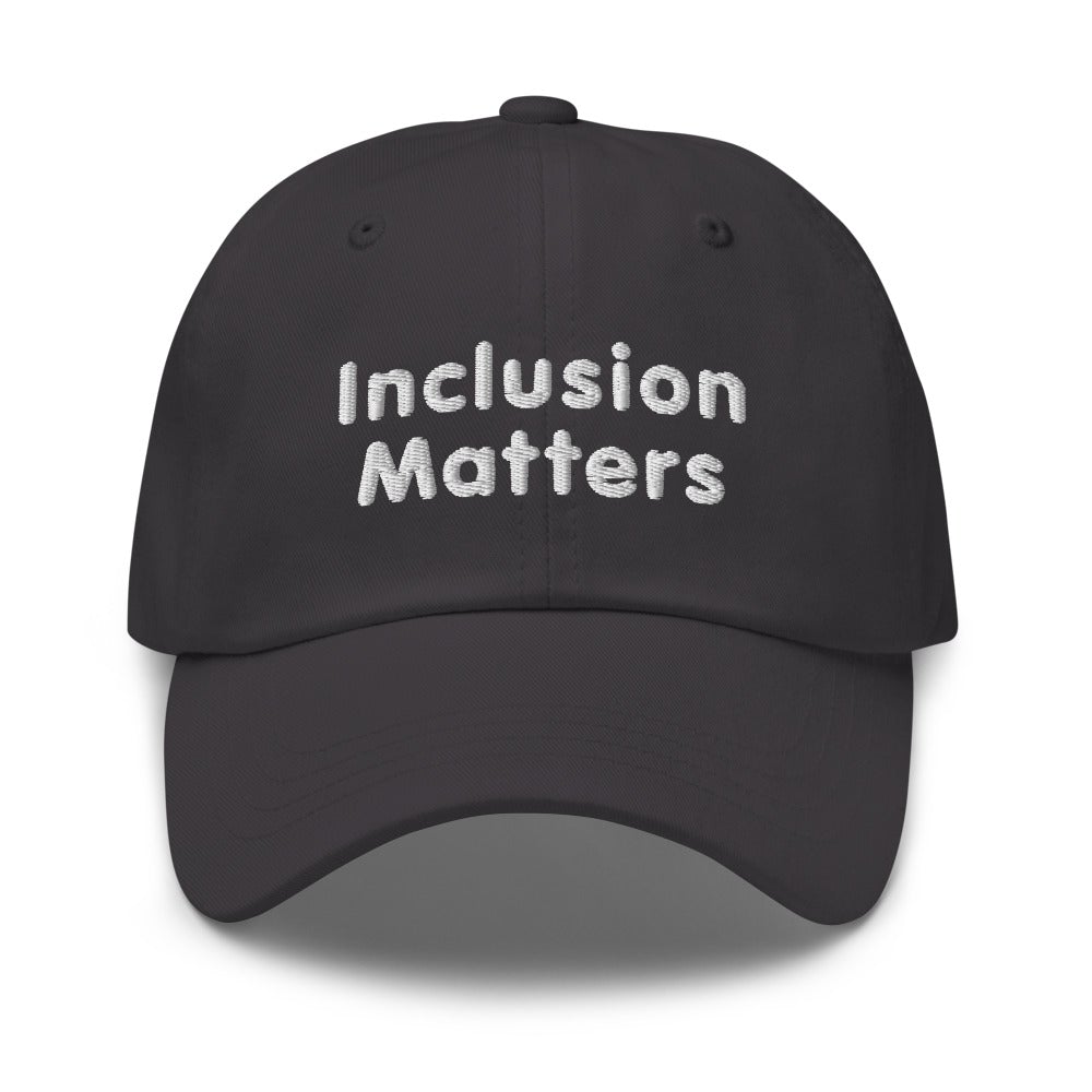 This is a photo of a dark-gray Inclusion Matters Baseball Cap. On the front of the baseball cap above the visor are two words, 'Inclusion Matters.' printed in white sentence case letters over two lines.