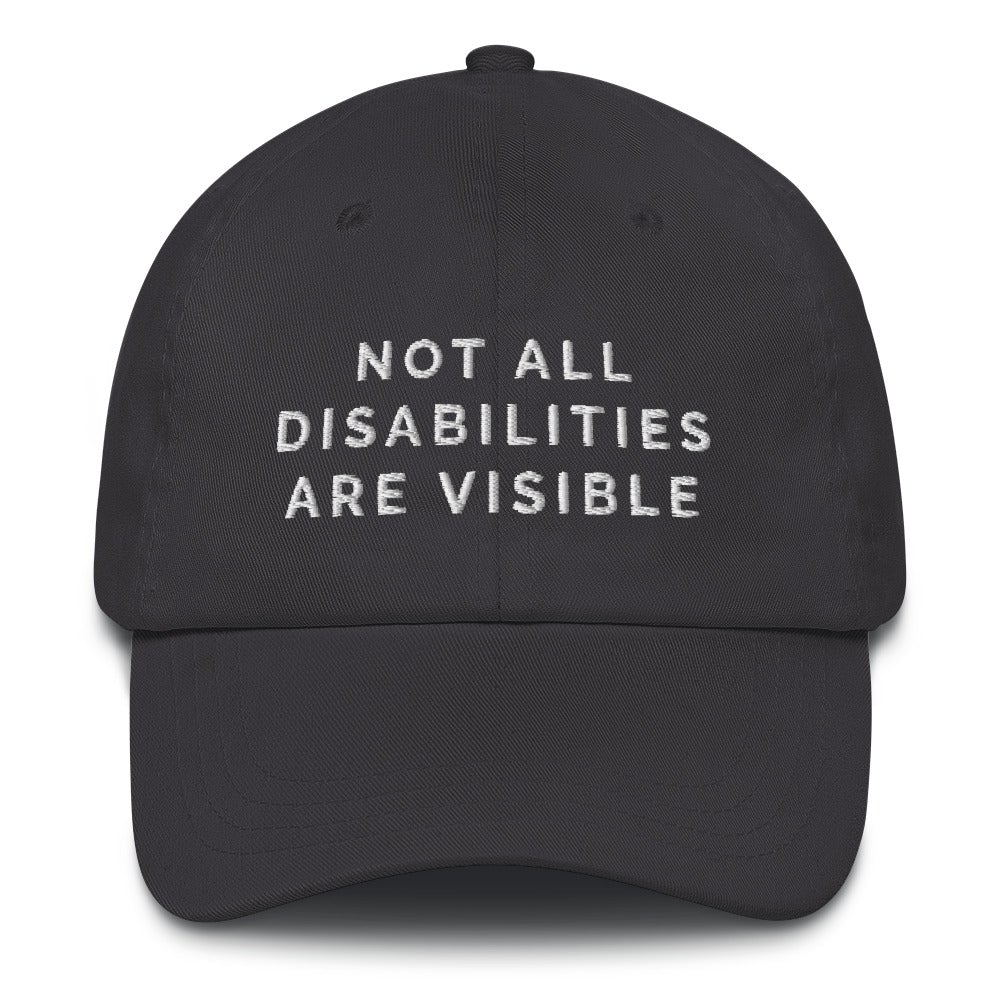 This is a photo of the front of a dark-gray Not All Disabilities Are Visible Cap. In the middle of the cap, in white embroidered upper case letters, is the phrase "Not All Disabilities Are Visible." The phrase is on three lines: (1) not all, (2) disabilities, (3) are visible.