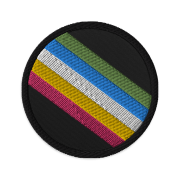 This is an image of an embroidered Disability Pride Flag Patch. In the middle of the black patch, there are five diagonal stripes in this order: red, yellow, white, blue, and green (when looking from the bottom up).