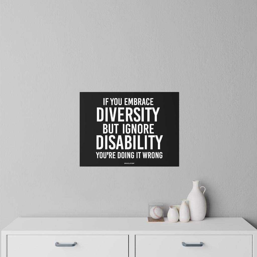 This is a photo of an Embrace Diversity decal. In the middle of the decal is the phrase, printed in white upper case letters, "If you embrace diversity, but ignore disability, you're doing it wrong." The phrase takes up 75% of the decal. At the bottom of the decal, in small white upper case letters, is the brand name URevolution. The size of the decal is 24" x 18". The decal is positioned on a gray wall above a chest of drawers.