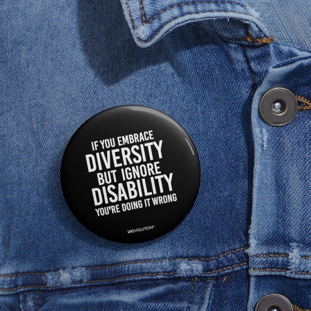 Embrace diversity pin. The embrace diversity pin features the phrase, printed in white upper case letters on a black backgound, "If you embrace diversity but ignore disability, you're doing it wrong." The embrace diversity pin is pinned on a denim jacket.