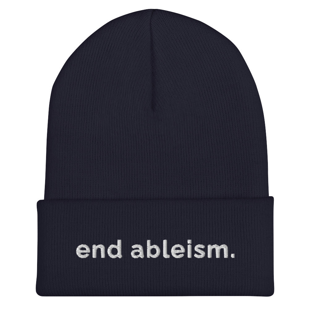 A navy End Ableism Beanie has the words 'end ableism.' embroidered in white lowercase letters on the front of the beanie.