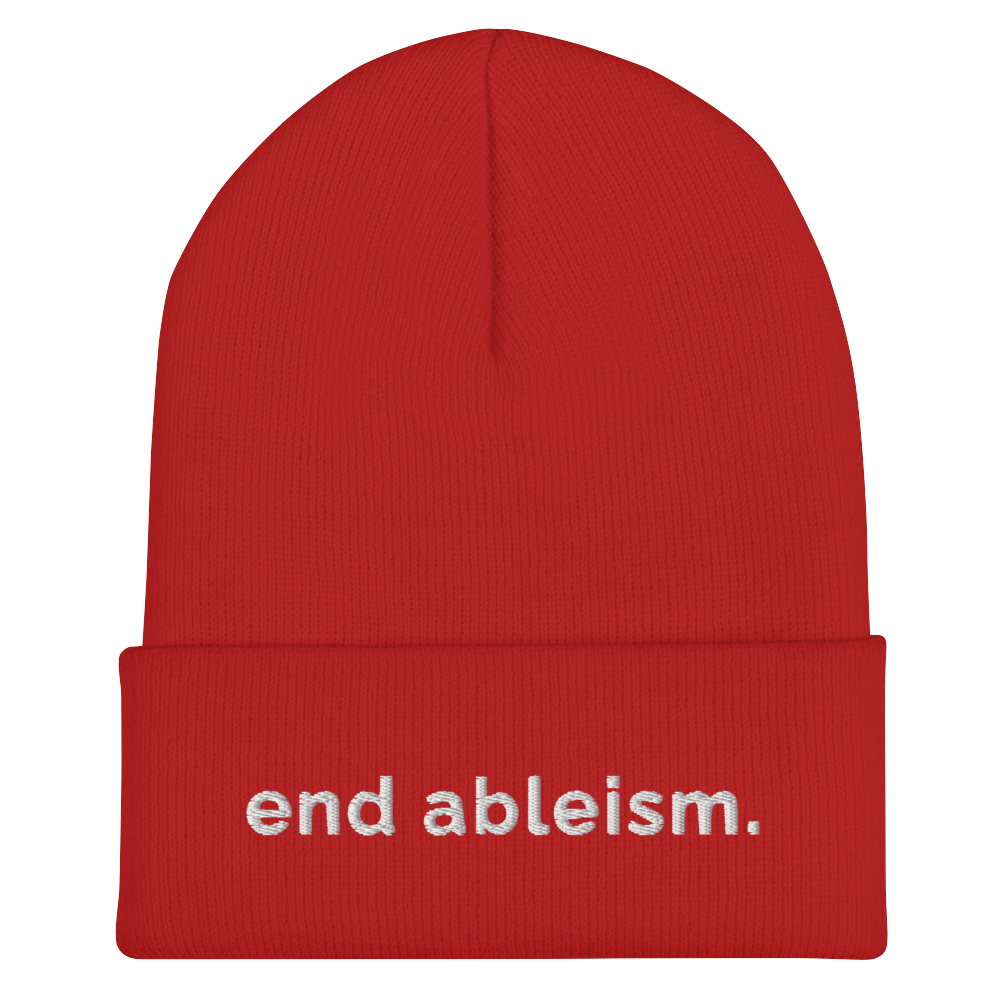 A red End Ableism Beanie has the words 'end ableism.' embroidered in white lowercase letters on the front of the beanie.
