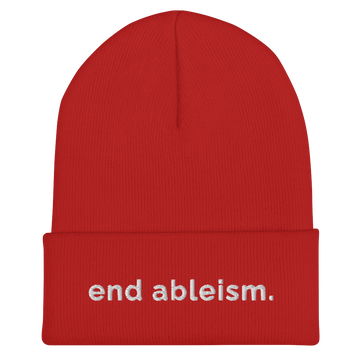 A red End Ableism Beanie has the words 'end ableism.' embroidered in white lowercase letters on the front of the beanie.