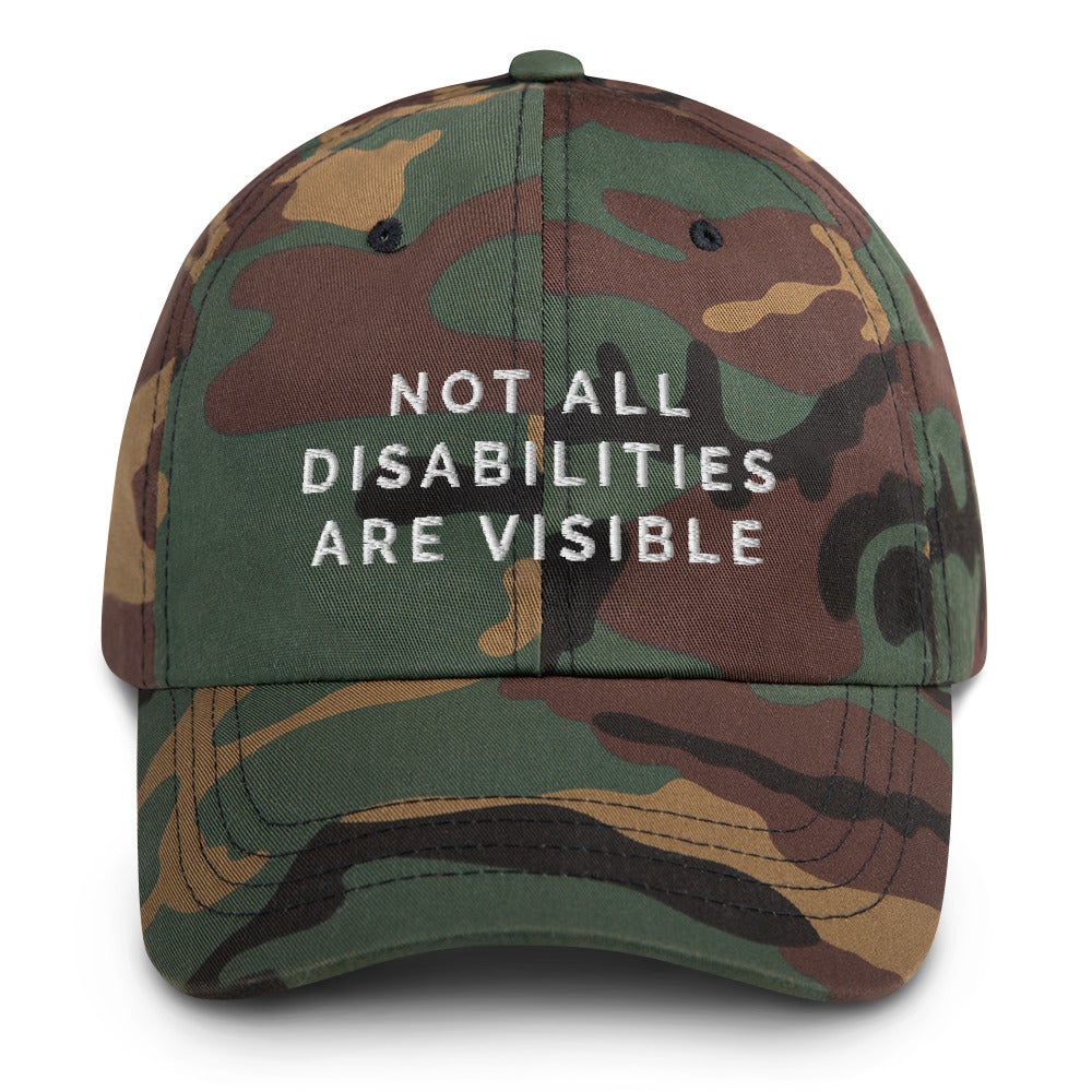 This is a photo of the front of a green-camo Not All Disabilities Are Visible Cap. In the middle of the cap, in white embroidered upper case letters, is the phrase "Not All Disabilities Are Visible." The phrase is on three lines: (1) not all, (2) disabilities, (3) are visible.